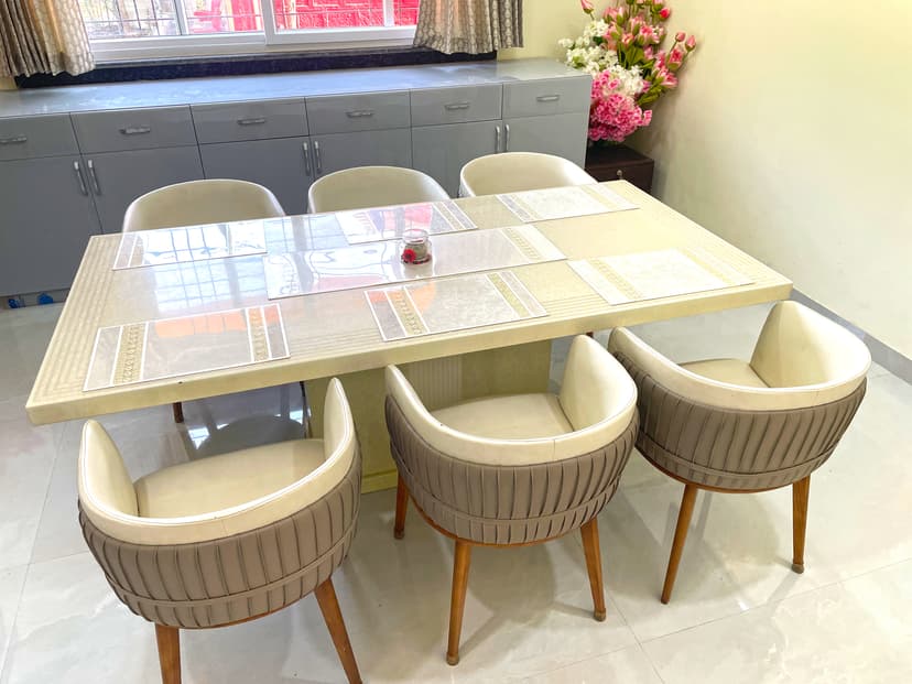 Close-up of dining area with designer table and cushioned chairs near a bright window