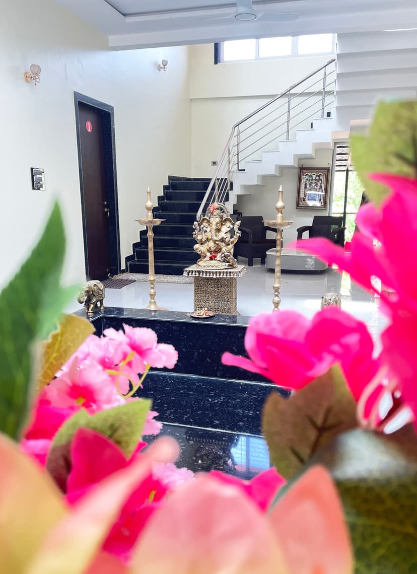 Ganesh idol centerpiece inside Kokan Kinara Villa with a staircase in the background and floral foreground