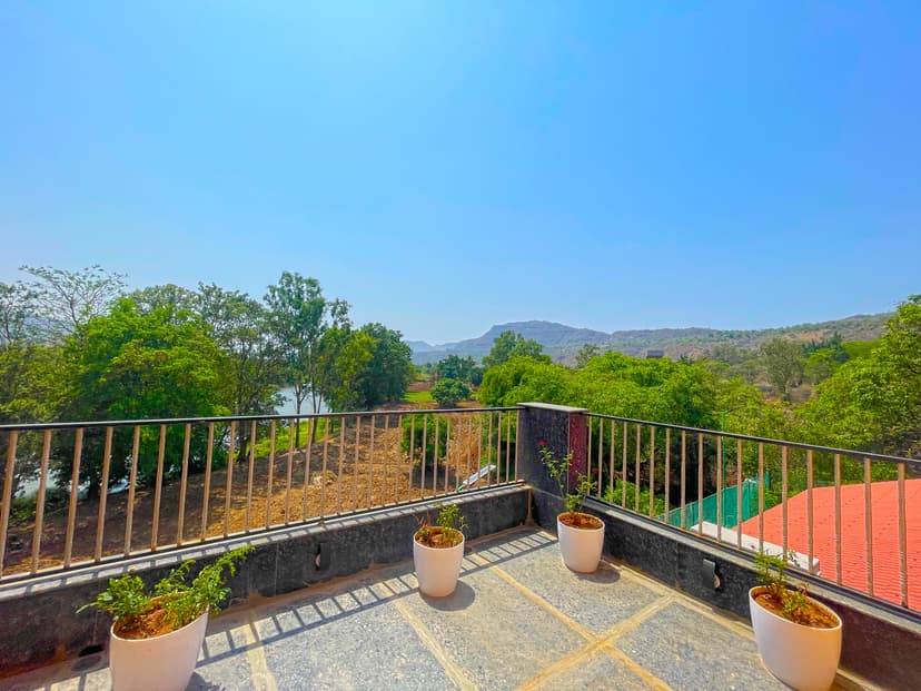Terrace view from Kokan Kinara Villa showing river, mountains, and potted plants on the railing