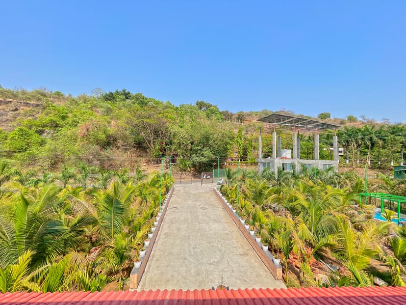 Aerial view of the villa's entrance surrounded by palm trees, with solar panel structures in the background