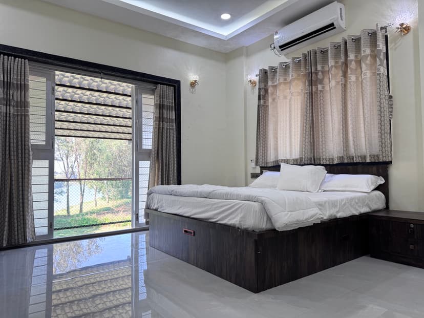 Bedroom with scenic river view from the balcony at Kokan Kinara Villa
