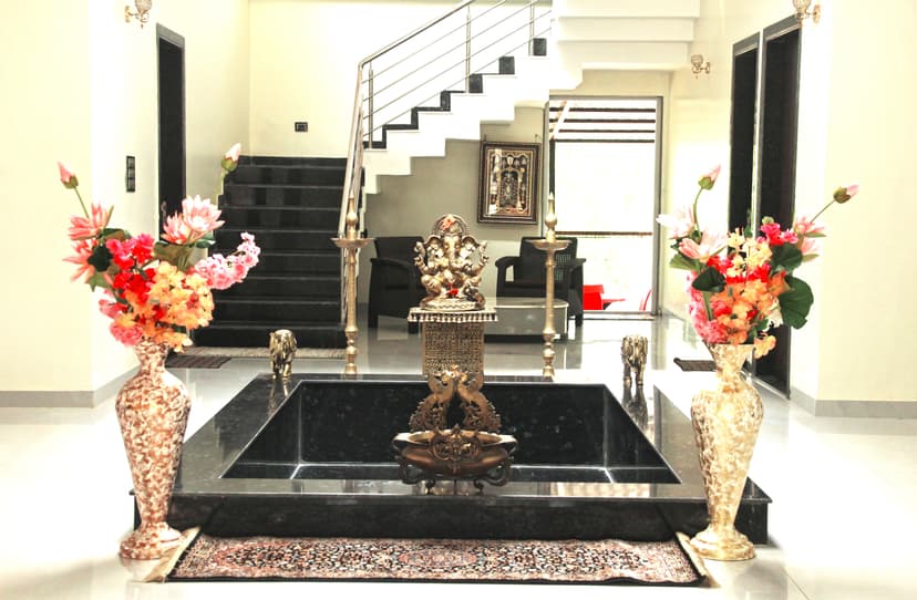 Grand indoor décor featuring Ganesh idol, floral vases, and black marble platform with staircase backdrop