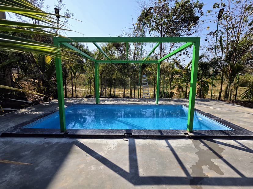 Swimming pool at Kokan Kinara Villa with a green metal frame and forest backdrop