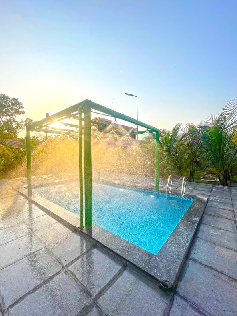 Outdoor swimming pool at Kokan Kinara Villa with mist spray setup at sunrise